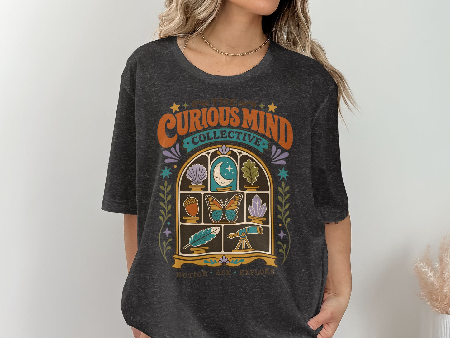 Dark grey t-shirt with "The Curious Mind Collective" graphic and window motif.