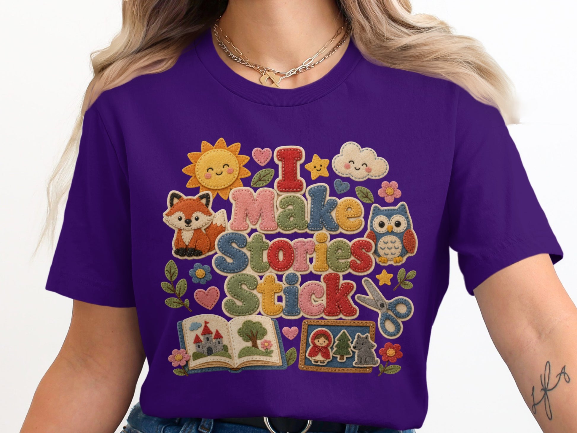 Purple t-shirt with "I Make Stories Stick" design featuring cute characters.