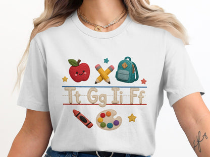 White t-shirt with felt school icons: apple, pencils, backpack, crayon, and paint palette.