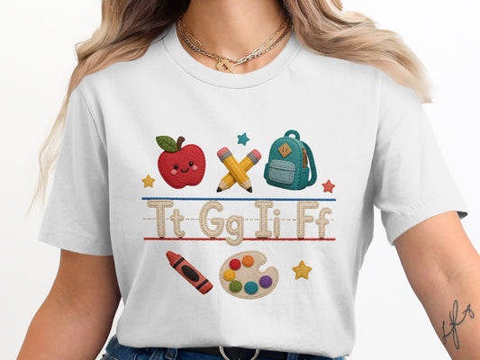 White t-shirt with felt school icons: apple, pencils, backpack, crayon, and paint palette.