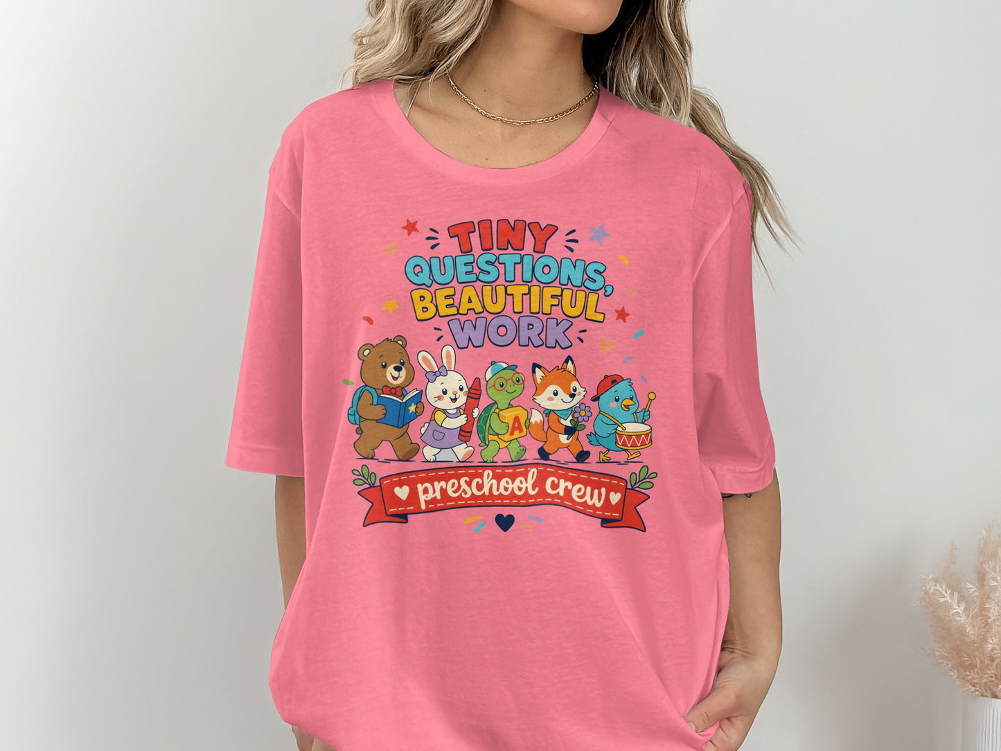 Pink t-shirt with "Tiny Questions Beautiful Work Preschool Crew" and cartoon animals.