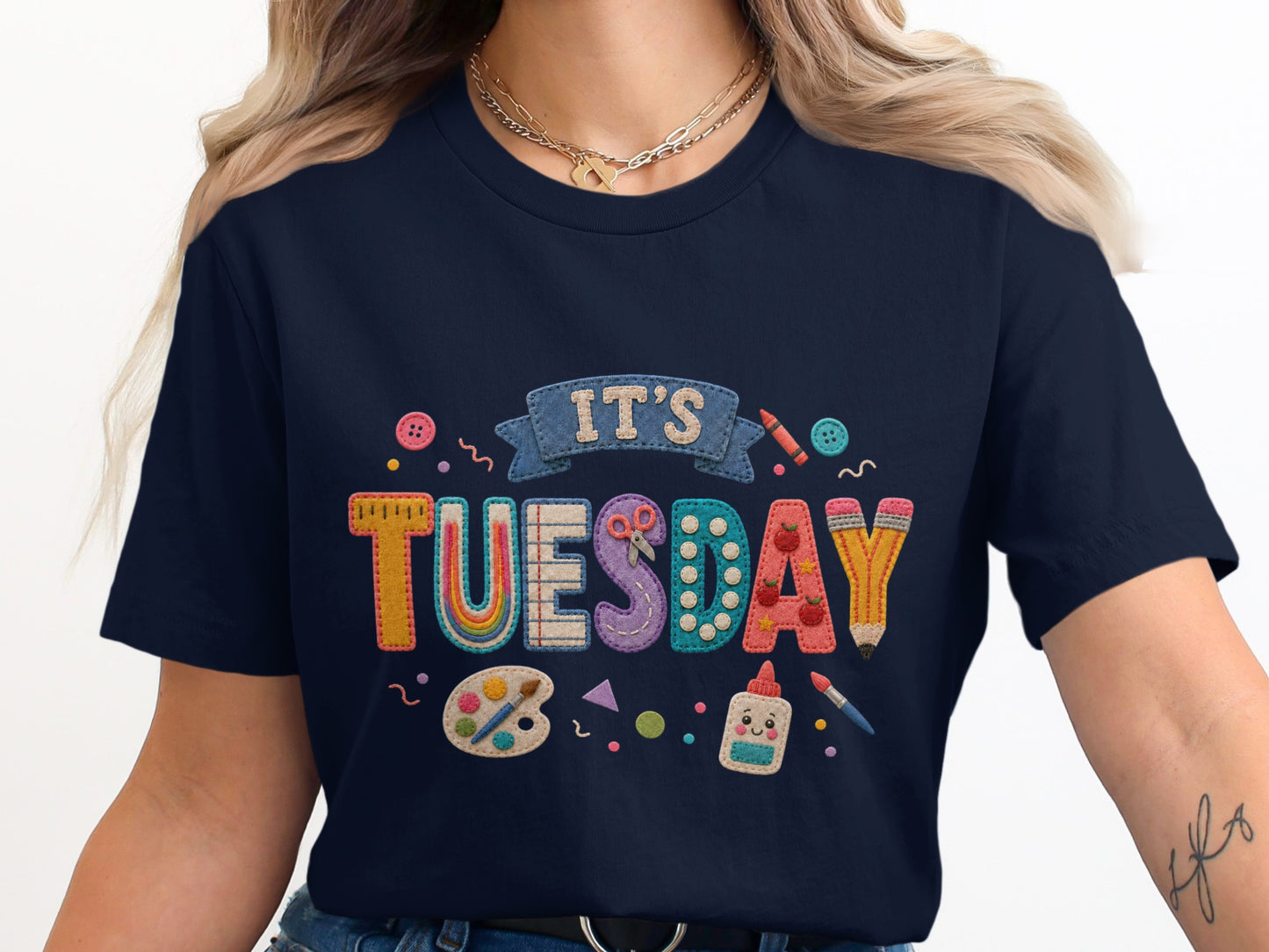 T-shirt with "It's Tuesday" in colorful, textured letters and craft supplies.