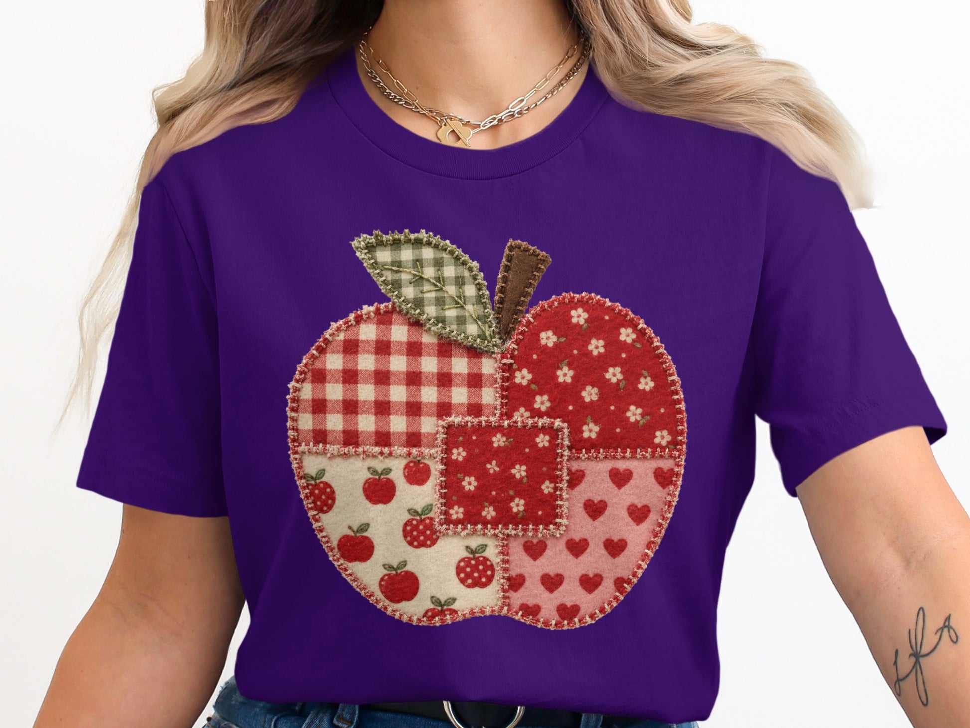 Purple t-shirt with a stitched apple graphic made of assorted fabric patterns.