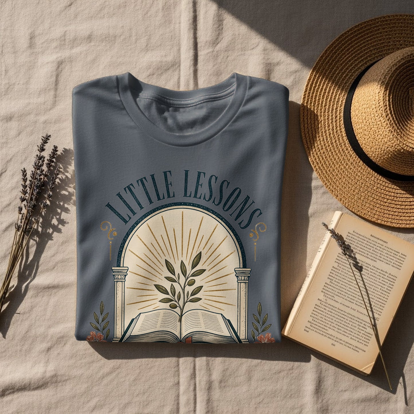 Steel blue t-shirt with "Little Lessons" text and an open book with a plant.