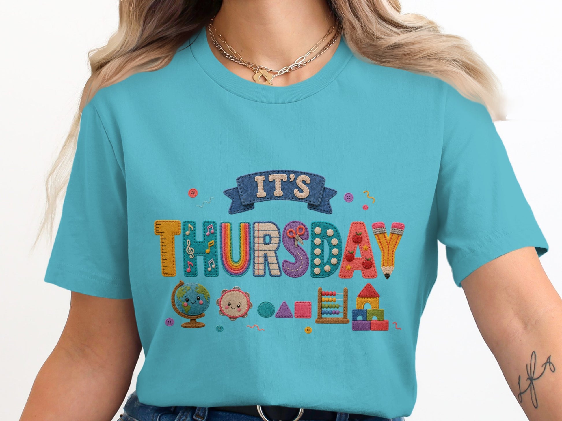 Turquoise t-shirt with "IT'S THURSDAY" text surrounded by cute school supplies.
