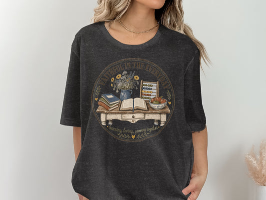 T-shirt with circular graphic featuring a desk with books, flowers, abacus, and fruit.